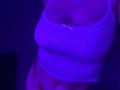 Olieri's white ribbed tank top with a small bow, covering her tits, and red thong, with purple lighting, highlighting her curvy, sexy, and attractive upper body.