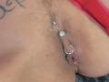 Le vagin de Shanna, avec un piercing en forme d'anneau en argent et une barre ornée de bijoux, ainsi qu'un petit tatouage sur le côté droit. Un morceau de tissu rouge est partiellement visible..
