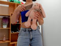 Steisii holding a pink stuffed bunny, wearing a blue tube top and high-waisted, button-down, denim shorts, with hands in pockets.
