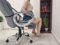 JoannaSia sitting on a gray office chair, wearing a lace bra and denim shorts, showing her bare ass and legs, with red high heels in a wooden shelf.