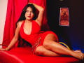 LilyConorr with big tits, curvy ass, wearing a red dress, lying on a red chair, hand in hair, long black hair, red lipstick, gold bracelet, sexy, confident.