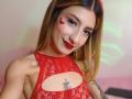 Kaiix with red lace top, red lipstick, heart makeup on cheek, nose ring, blonde hair, tattoos, smiling, showing armpit hair, small boobs, cute.