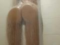 LilithDesire's wet, round ass is pressed against a foggy shower glass, with water droplets covering her lower back and buttocks, making her skin glisten.