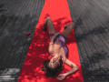 JocelynnKey lies on a red carpet, wearing a purple lace lingerie set, legs spread, with a glass of red wine to the left, dark wood floor, shadows.