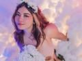 SweetyAliceHotX with wavy brown hair, flower crown, holding white roses, topless, pink and blue lighting, smiling, soft pink blush, cute, holding flowers in front of her tits.