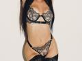 JaneWow's black lace bra and thong set, showing her tits and pussy, with matching lace stockings, standing against a white background. Her long black hair covers her face.
