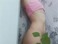 WollyMolly's pink panties are pulled down, exposing her bare ass and a tattoo on her side. A green leaf is in the bottom right.
