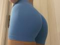 De strakke, blauwe korte broek van SandraSweet omhelst haar ronde, stevige billen. De gladde stof accentueert haar rondingen. Haar gebruinde huid is zichtbaar aan de onderkant..