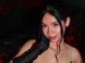MelodyGloss with black hair, pinkish skin, and pouty lips, has a black glove touching her cheek, wearing a silver necklace, and showing her bare shoulders.