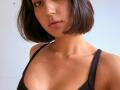 HeikeCarchi with a short, dark brown bob, freckled face, nose ring, and parted lips, wearing a black tank top, showing her small, bare boobs and collarbone.