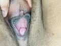KarlaWild's pussy, showing her dark-skinned labia being spread to reveal her pink, swollen clitoris and inner vaginal folds. Her hand is gently pulling her labia apart.