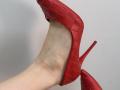 Tattiya's foot in a red, croc-patterned stiletto heel, showing her pale skin and the heel's pointed tip, with the shoe partially off and her ankle visible.