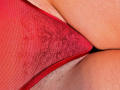 A red mesh thong with a lace pattern is pulled to the side, revealing a hairy pussy and part of a fat, pale, hairy ass.