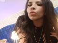 VioletaStone with pouty pink lips, long black hair, wearing a black top with cutouts, and a silver necklace, looking at the camera with slightly raised eyebrows.