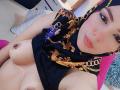 AliceKayleigh with a black and gold patterned hijab, showing her bare tits and small brown nipples, looking at the camera with a slight pout.