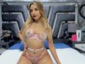 CloeRouss with long blonde hair, wearing a pink floral lingerie set, sitting on a bed, showing her tits and pussy, tattoo on right side, red lipstick, confident smile.