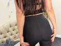 Stefanni's ass is in tight black leggings, her hands resting on her butt cheeks. She's wearing a black sports bra, her long brown hair down. She's in a room.