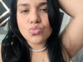VivianaThompson has pink pouty lips, black hair, and a pearl necklace. She's pouting with her right arm raised, showing a cute, slightly chubby face.