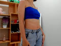 Steisii has a slim, tan-skinned body with small tits in a blue strapless top and light blue, high-waisted jeans, standing with hands near her jeans.