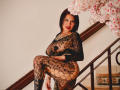 DonnaJones with black lace outfit, showing her tits and ass, sitting on stairs, cherry blossoms in background, short black hair, red lipstick, tattoo on chest.