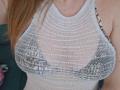 Les seins de Marriam sont visibles à travers un débardeur blanc en mesh semi-transparent, avec un soutien-gorge à motifs en dessous. Ses cheveux blonds sont partiellement visibles..