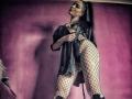 JustIzabel with long black hair, wearing a black dress, fishnet stockings, and black heels, showing her ass and tits, looking down with a sultry expression.