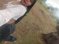 CataMoreno with long black hair, wearing a white lace top and blue jeans, showing her ass in a grassy park, looking back with a slight smile.