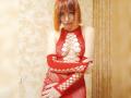 LaylaHottyX with red bob, wearing a red fishnet dress exposing her tits and arms, standing with arms crossed, looking at the camera.