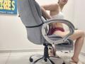 JoannaSia sits on a gray office chair, wearing a white lace bra and pink panties, exposing her pussy, with her ass slightly raised, in a bright room.