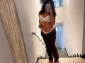 SofiaPassionne in a mirror selfie, wearing a white lace bralette, brown pants, and no underwear, exposing her tits and pussy. She has curly hair and a tan skin tone.
