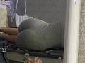 KaiaLein's big ass in a tight, grey, ribbed dress, lying on a bed with a white, ornate mirror in the foreground and a black bag on the left.