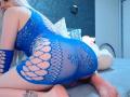 CoquineElise with long blonde hair, wearing a blue lace fishnet dress, on her knees, showing her ass through large oval cutouts, on a grey bed. Tattoo on her ankle.