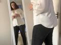 Elliance stands in front of a mirror, wearing a white button-up shirt and black pants, with her ass slightly visible. She's looking at herself, fiddling with the shirt.