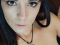 OrianaLaFrancaise has dark brown eyes, black eyeliner, and black hair. She's topless with a necklace, showing a small black mole on her left cheek and pink lips.