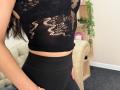 Stefanni's black lace crop top with cut-out patterns reveals her small boobs. She wears black high-waisted leggings, and her long dark hair is partially visible.