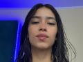 LaurentRay has wet black hair, hoop earrings, and slightly parted glossy pink lips. Blue light is in the background. LaurentRay's brown eyes are half-open with subtle eyeliner.