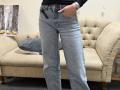 Dalaila's ass is in a pair of blue, slightly faded, flappy jeans with her hand in the pocket. She's wearing a black shirt and a silver watch.