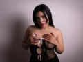 AdrianaPaul with black lace dress, holding handcuffs, covering her tits with hands, red lipstick, long black hair, tattoo on right arm, white background, slightly seductive look.