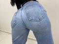 OliviaGranda's tight blue jeans emphasize her round ass, showing two small back pockets with visible stitching. Her black top is partially visible at the top.