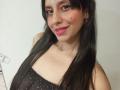 MadissonFontaine with long black hair, pink lipstick, and a black sparkly dress, smiling with small tits, a nose boop, and a bindi on her forehead.