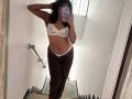 SofiaPassionne in a mirror selfie, wearing white lace bra, brown pants, and white panties, showing her small tits and ass, with curly black hair and arm tattoos.