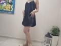 JoannaSia in a dark blue, loose, sleeveless dress, standing with hands on her dress, bare feet, and no shoes, showing her ass and legs, in a plain room.