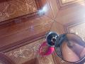 Caylin's wet, glistening pussy is reflected in a round mirror with a pink handle, resting on a wooden floor with intricate patterns. Water droplets are visible.