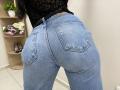 OliviaGranda's blue denim butt is facing the camera, showing her tight, denim-covered ass with visible back pockets. She's wearing a black, lace top, and her belt is black.