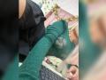 SabrinaColle's grünes Mesh-Oberteil mit sichtbaren Brüsten, schwarzer Rock, blonden Haaren und blauen Nägeln, die ein Selfie vor einem Laptop macht, mit einem rosa Kissen und Ranken..
