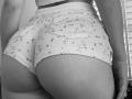SugarrX's ass in tight, floral-patterned ribcage shorts, showing their butt and upper thighs, with a slight waistband and visible pocket, in a black-and-white photo.