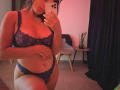 AmeliRoux with dark purple lace bra and matching panties, showing her tits and pussy in a mirror selfie, holding a white iPhone, in a softly lit room.