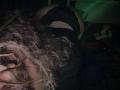 KrystalBerkovitch, with curly blonde hair, on all fours, wearing black lace panties, exposing her ass. Dark, moody lighting, shadowy background. Her face partially obscured by hair.