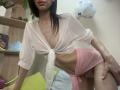 Valnes with pale skin, dark hair, small tits, wearing a tied white shirt, pink sheer shorts, exposing her pussy, leaning forward, slightly smiling, in a bedroom.