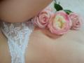 AmeliaMaiv's white lace panties, showing her soft, pale skin, with pink roses resting on her lower belly and upper thigh. Her navel is slightly visible.